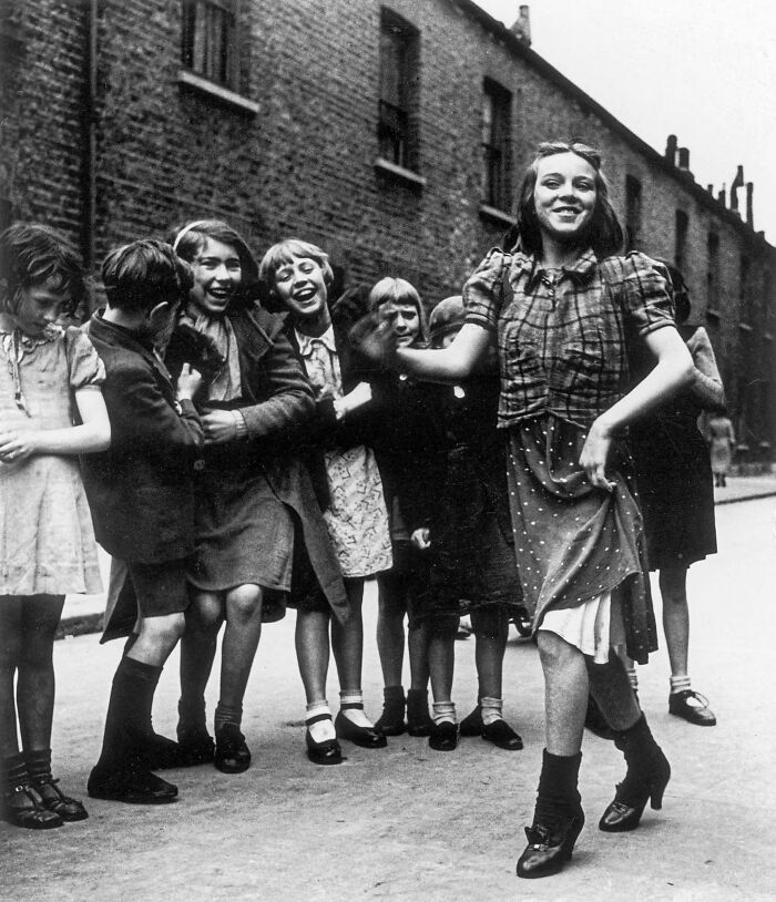 Group of children joyfully watching a girl dancing in a street
