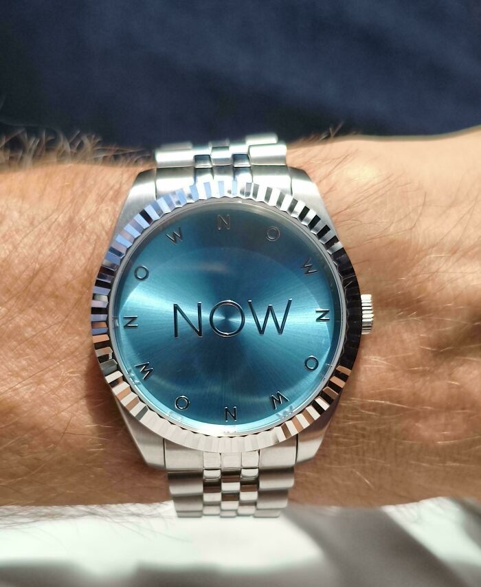 Minimalist watch design with word NOW displayed on the face