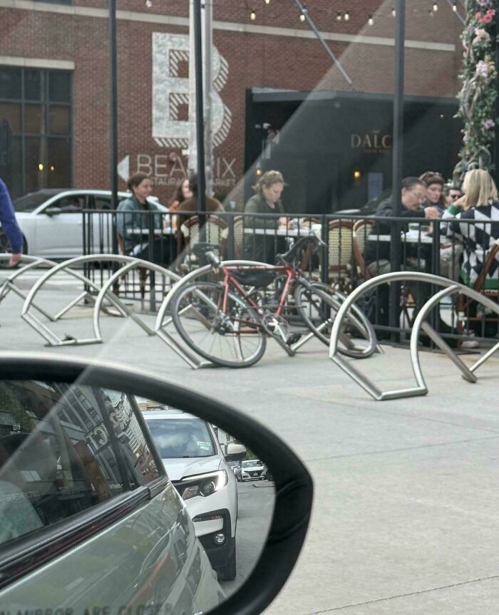 Urban bike rack design near a restaurant with people dining outside
