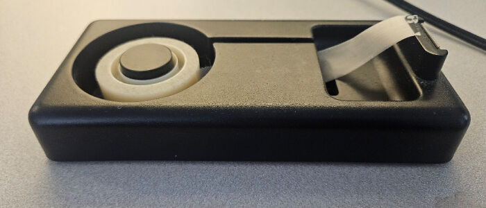 Black tape dispenser missing the tape roll making it unusable