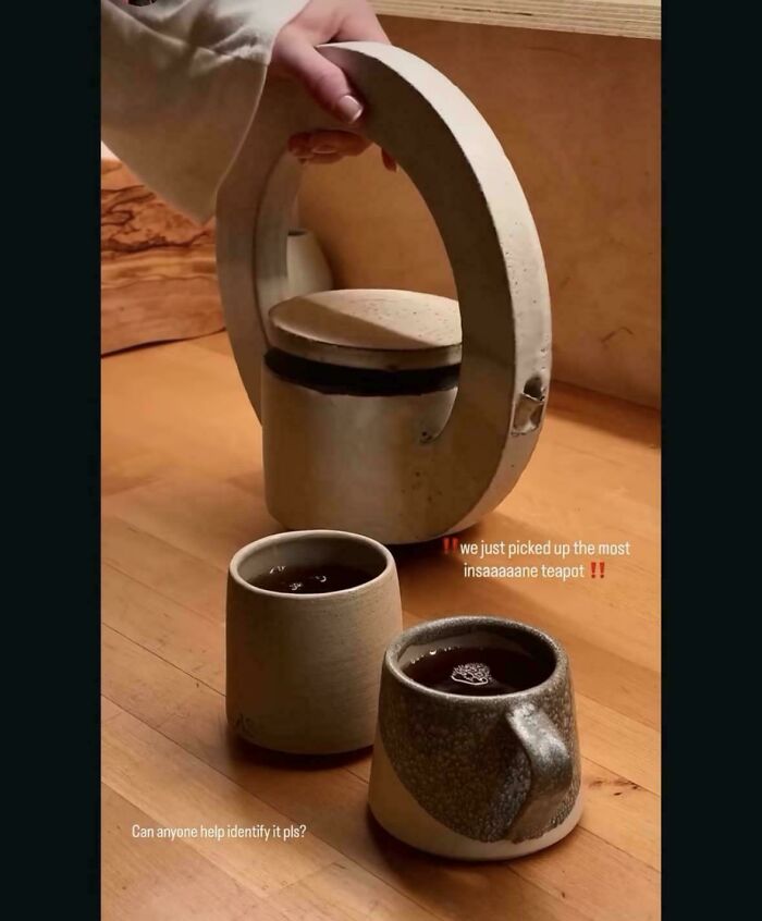 Unique circular handle teapot with two ceramic cups on wooden table