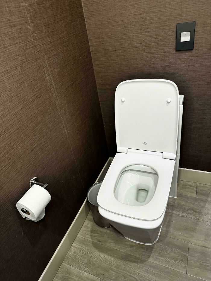 Toilet with lid and nearby toilet paper holder in modern restroom