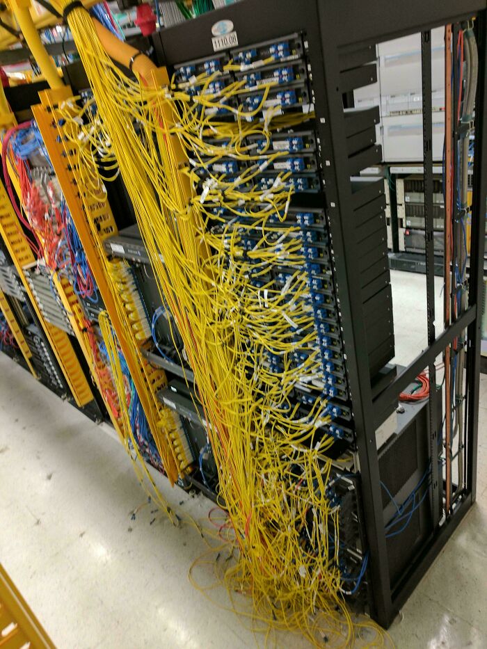 A server rack overflowing with a tangled mess of yellow cables, a chaotic example of electronics fails.