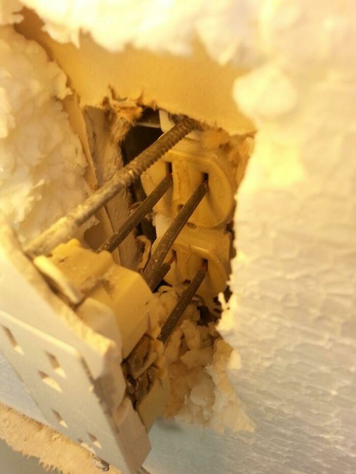 A damaged electrical outlet with exposed wiring and debris, highlighting electronics fails.