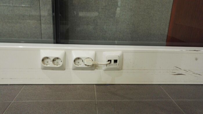 An image showing an electrical outlet with a charger connected to an adapter, illustrating an electronics fail.