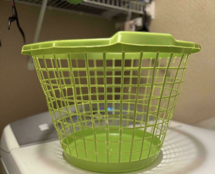 A bright green plastic laundry basket on a white washing machine, reflecting the tangible objects of consumerism.