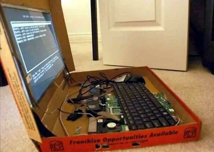 A computer built inside a pizza box, with a monitor, keyboard, and mouse, a clear electronics fail.