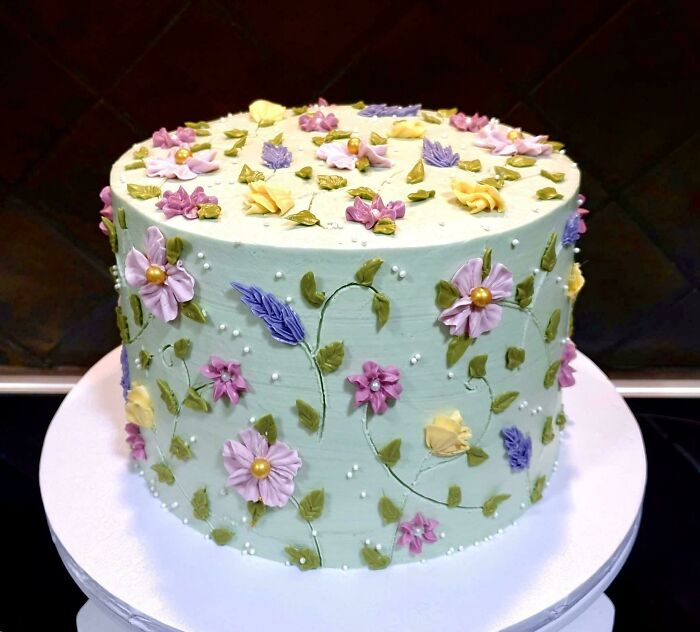 An elaborately decorated cake with delicate floral designs in various colors, a beautiful bakers treat.
