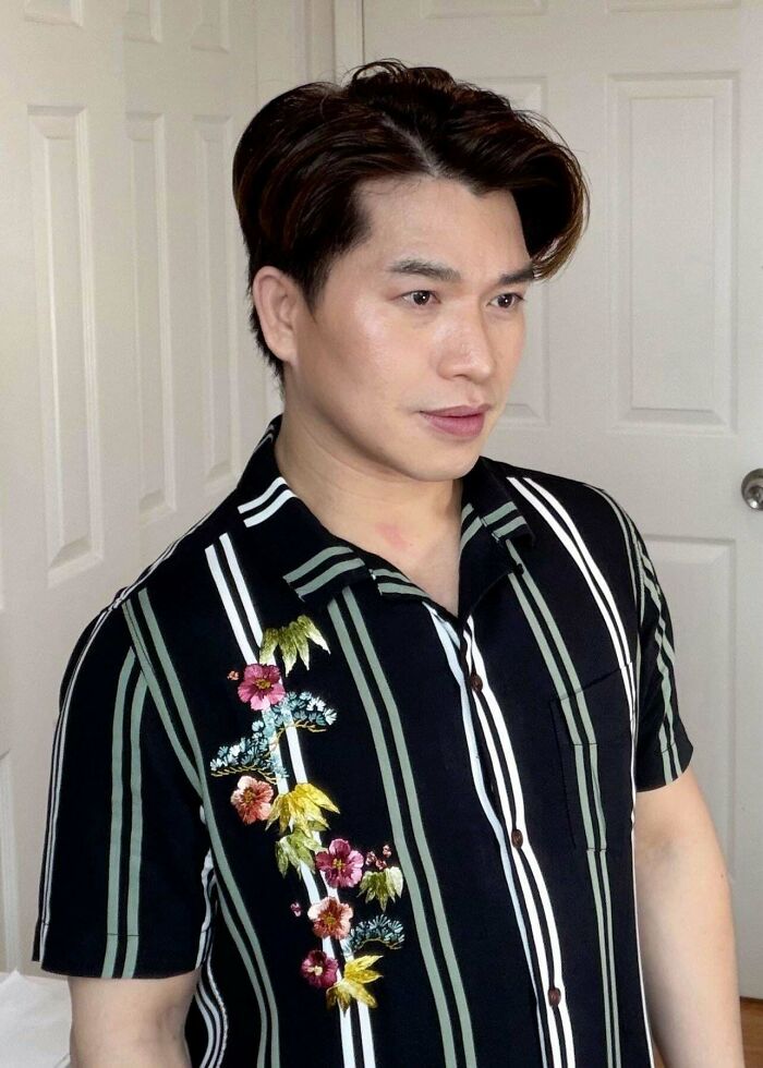A man wearing a black and white striped shirt with embroidered flowers, a handmade project with talent and patience.