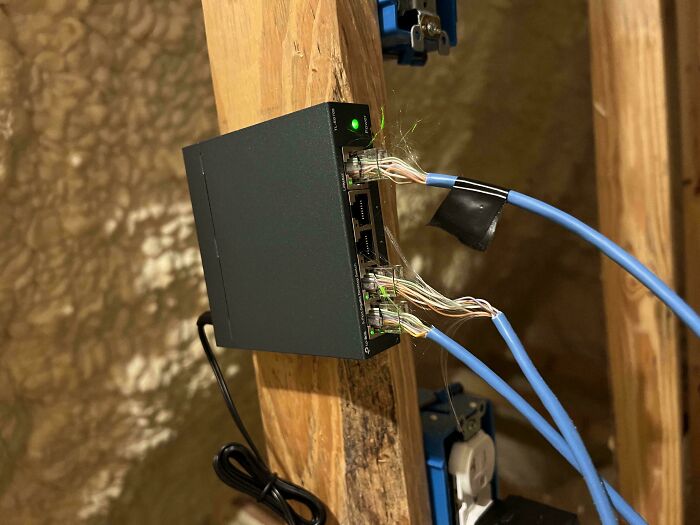 An Ethernet switch showing messy, frayed wires, taped-up connections, and dust, highlighting electronics fails.