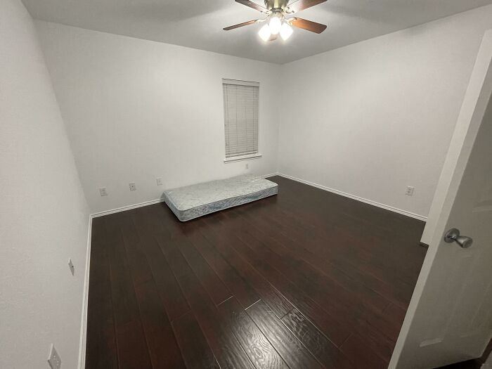 An empty room with white walls and a mattress on a dark wooden floor, symbolizing new beginnings for adoption stories.