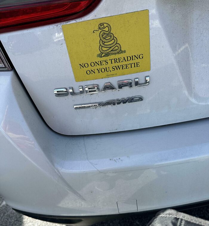 Yellow bumper sticker on Subaru reading no one's treading on you sweetie with coiled snake
