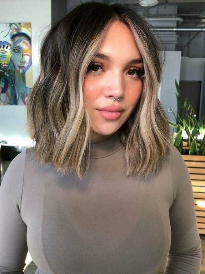 A woman with a beautiful, modern wavy bob hairstyle featuring face-framing highlights from a hair salon.
