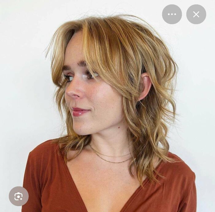 A woman with a stylish, wavy haircut, looking slightly off-camera.