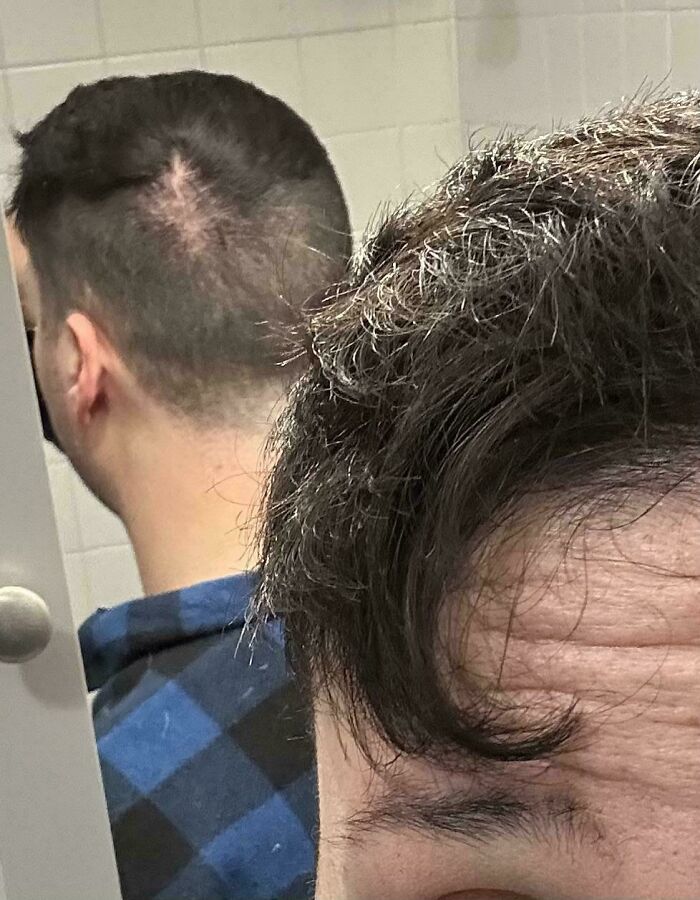 A man looking in a mirror, revealing unevenly cut hair at the back of his head, a clear hair salon disaster.