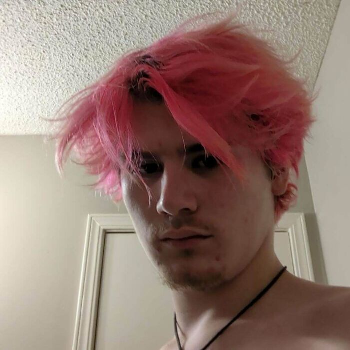 Young man with messy, bright pink hair, highlighting a hair salon disaster.