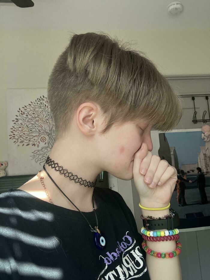 A person with a short, uneven haircut, covering their mouth in disbelief at a hair salon disaster.