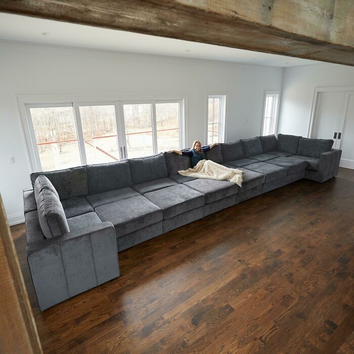 A massive, sprawling sectional couch with a person relaxing, a dream for an interior designer.