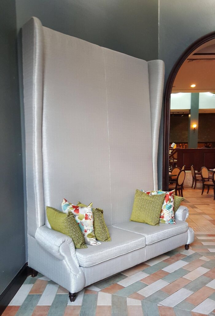 An exceptionally tall, elegant couch with throw pillows, a statement piece for interior designer aesthetics.
