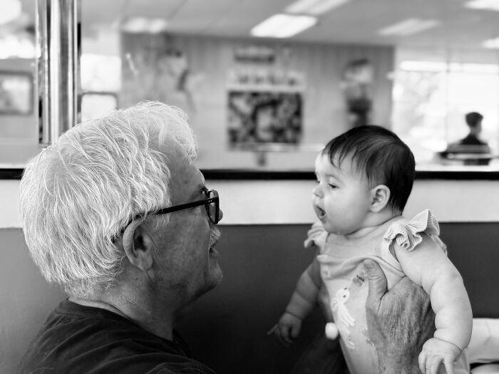 Amazing fathers: A black and white photo of a dad holding a baby, gazing at each other affectionately, highlighting amazing parents.