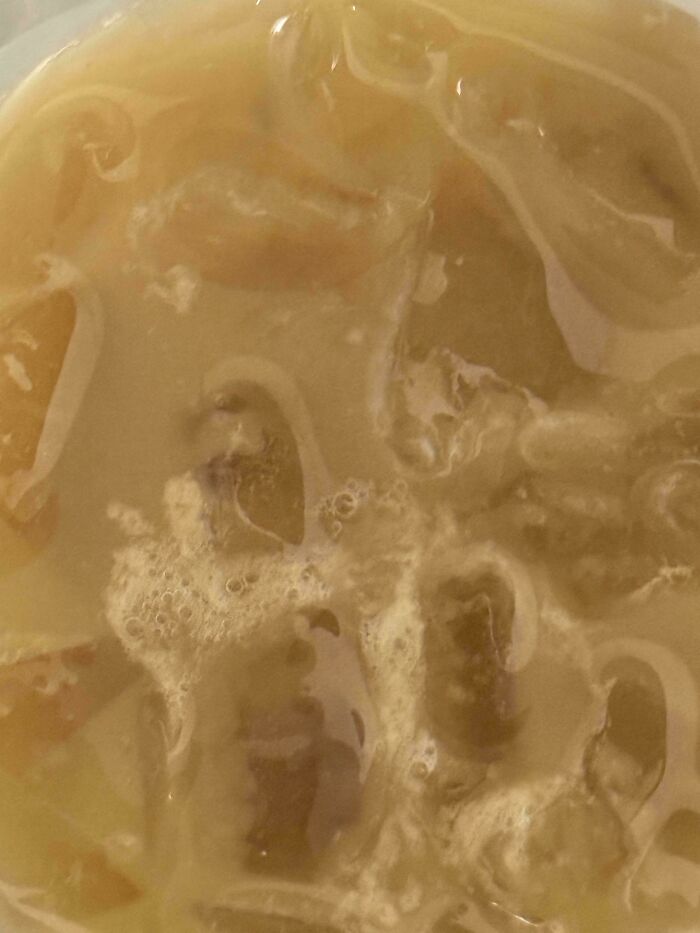 A close-up of a melted drink, likely from a food delivery fail, showing the ice has completely dissolved.