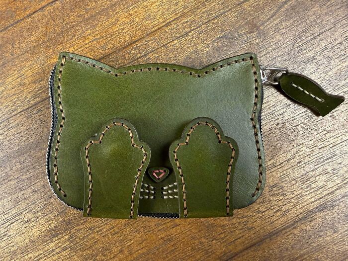 A handmade green leather cat-shaped pouch, a creative project requiring patience and talent.