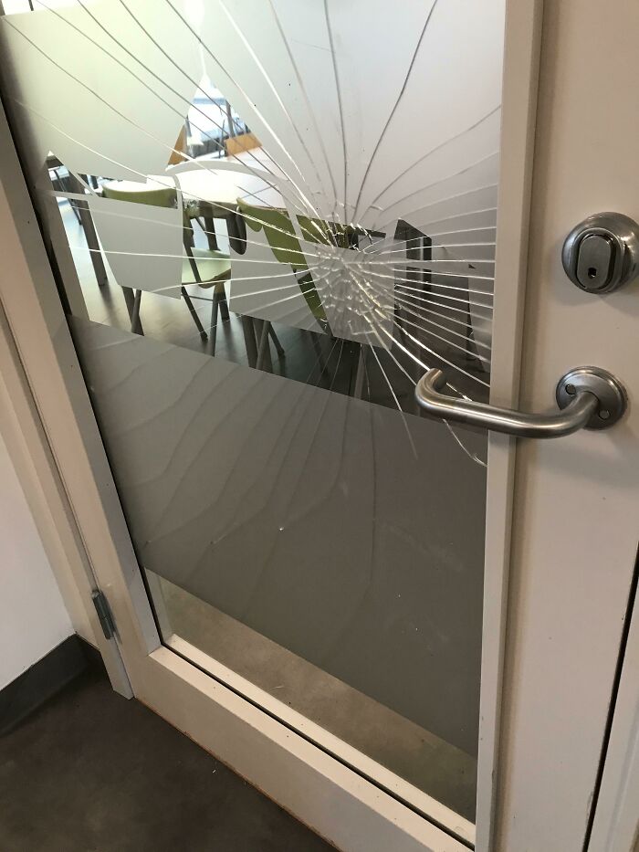 Broken glass door with spiderweb cracks inside school or classroom