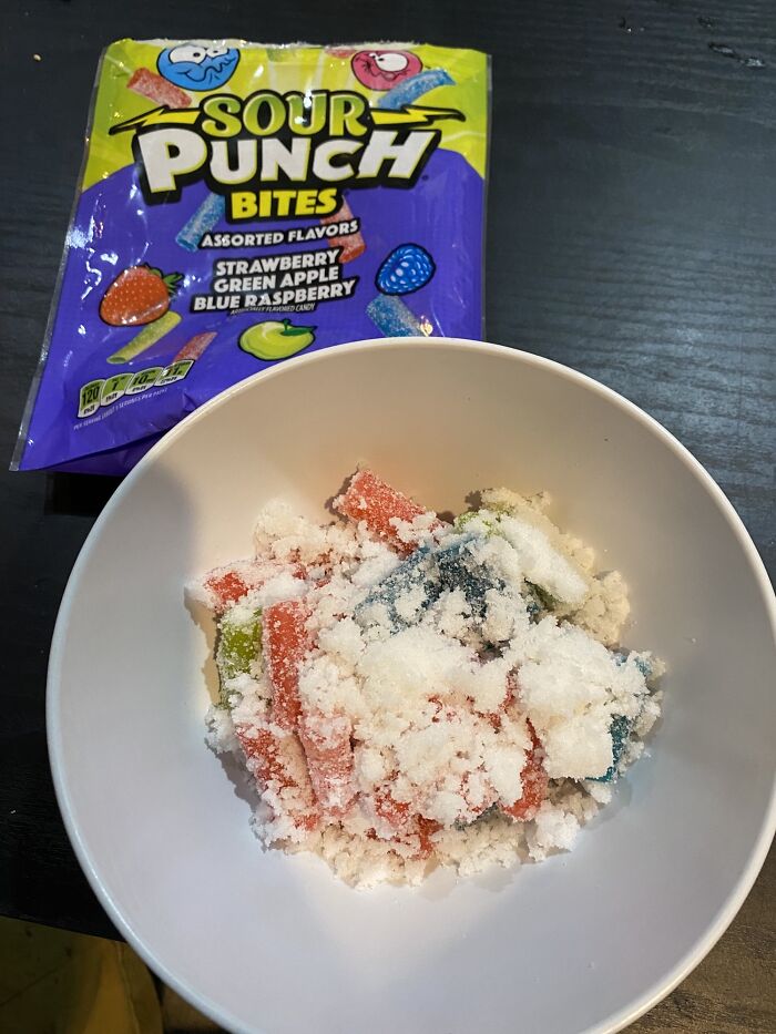 Sour Punch candy covered in sugar crystals in a bowl with packaging nearby