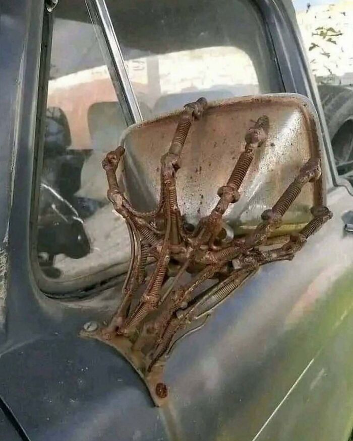 Rusty car mirror held by springs shaped like fingers in cursed images