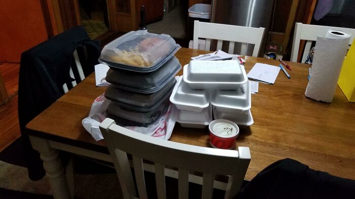 Infuriating food delivery fails: a kitchen table completely covered with numerous takeout containers, still packaged.