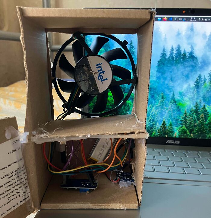 Cardboard fan setup for laptop, demonstrating makeshift electronics repairs and potential fails.
