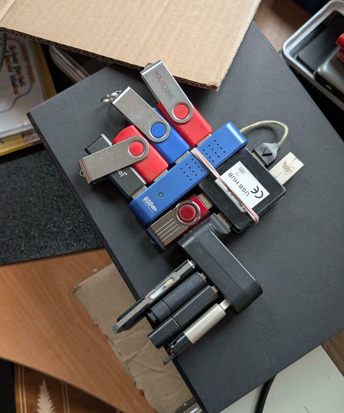 A cluster of USB drives and a USB hub on a black box, demonstrating a common Electronics Fails scenario.
