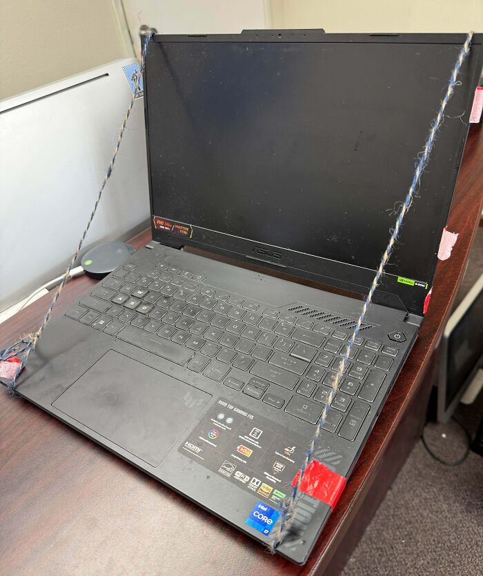 A laptop with its screen propped up by strings and tape, an example of creative yet precarious electronics fails.