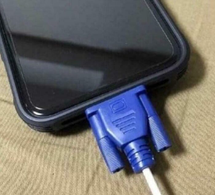 A smartphone connected to a large blue VGA cable, an example of an amusing electronics fail due to incorrect port usage.