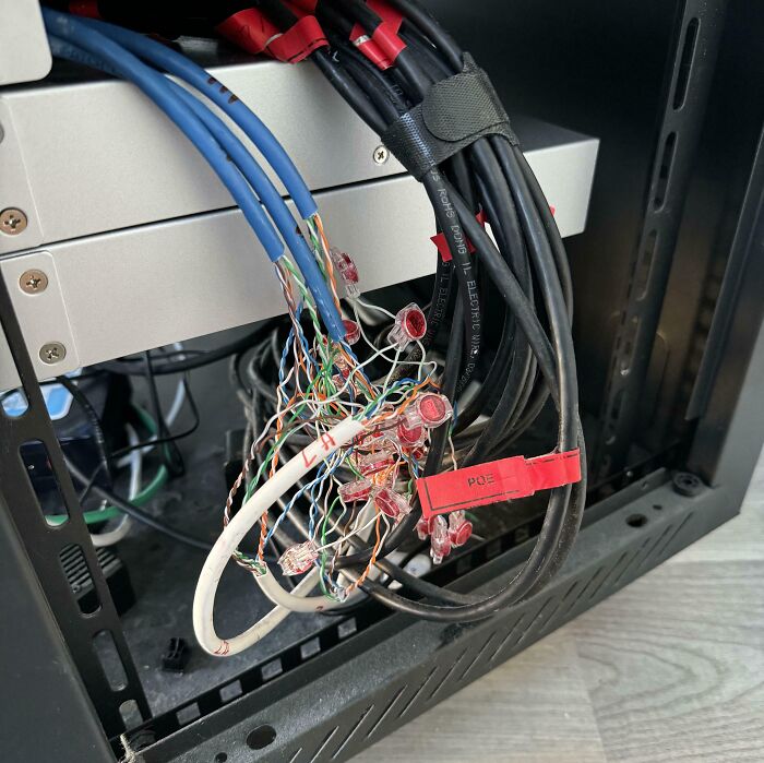 A messy tangle of wires and cables inside an open server rack, demonstrating electronics fails in IT setup.