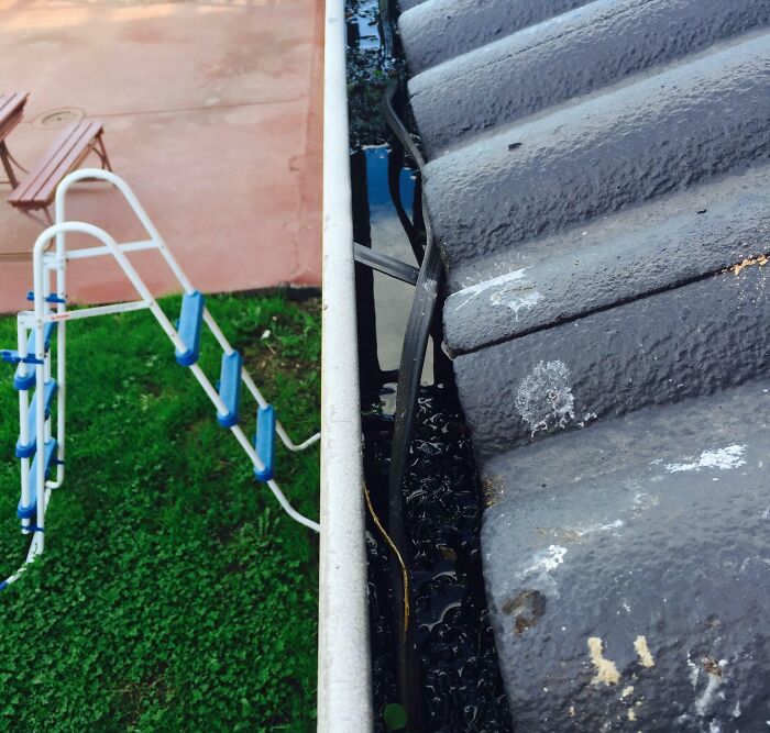 An extension cord improperly run through a rain gutter, a classic example of electronics fails and the work an IT guy deals with.