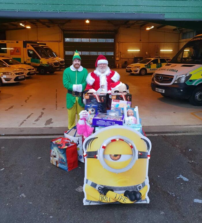 Santa and an elf with a pile of toys, showing the generosity of amazing fathers during the holidays.