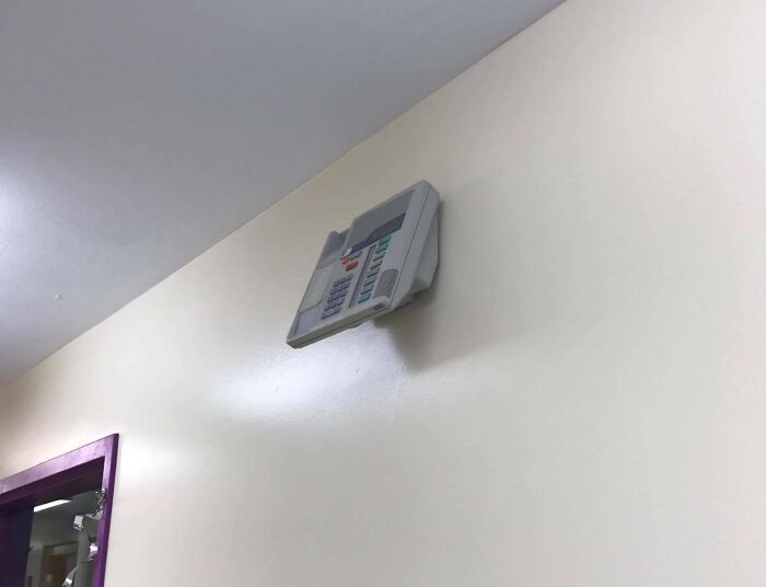 A badly installed wall-mounted electronic device hanging precariously, exemplifying electronics fails.