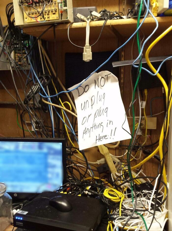A tangled mess of electronics fails with a sign warning not to unplug or plug anything in.