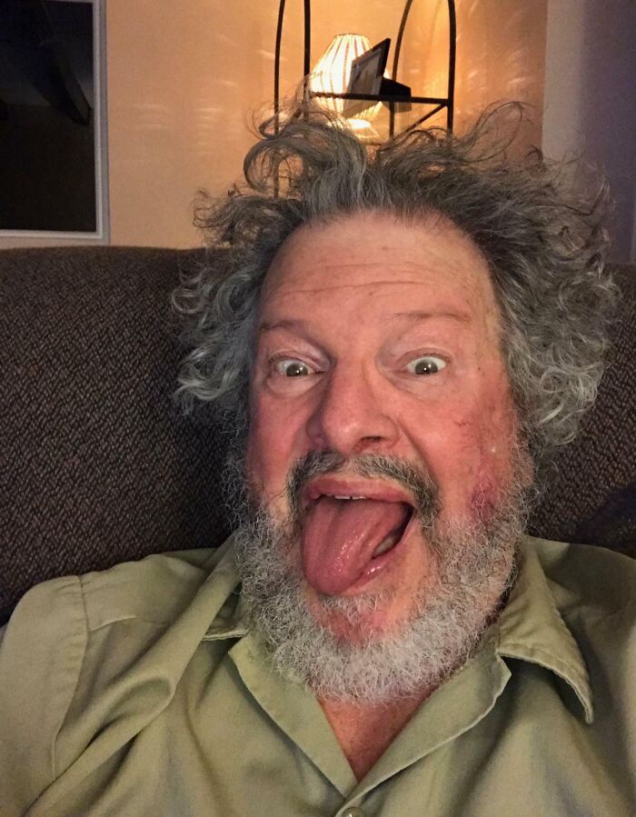 An amazing father with wild hair and a beard sticking out his tongue, displaying fun parents personality.