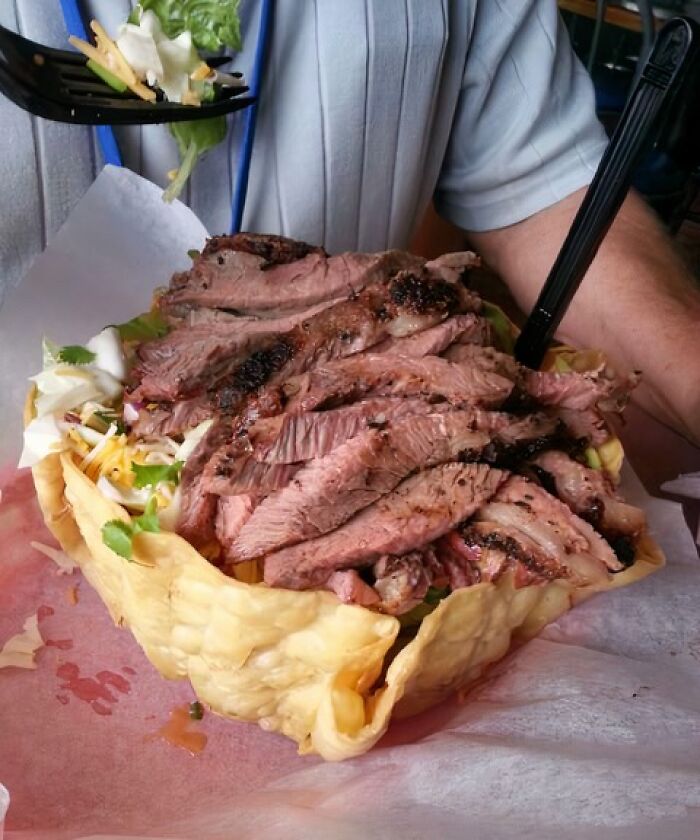 A father's meal: a giant taco salad bowl filled with sliced steak, cheese, and lettuce.