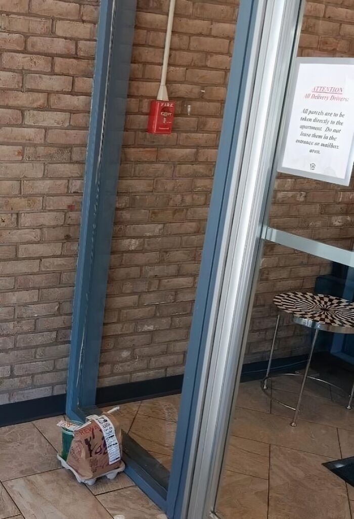 A food delivery package left precariously on the floor by a glass door, highlighting an infuriating food delivery fail.