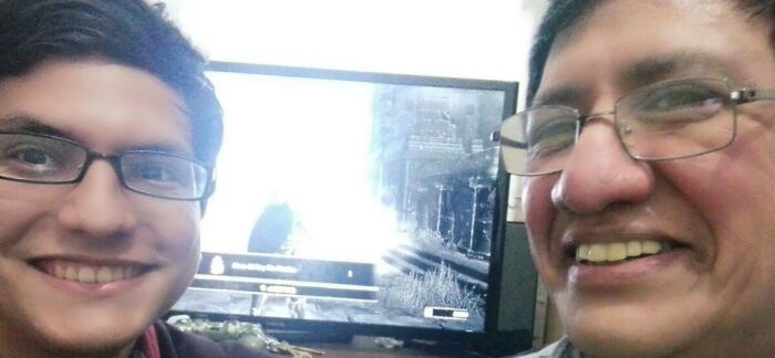 A happy father and his child smiling, taking a selfie while playing a video game together.