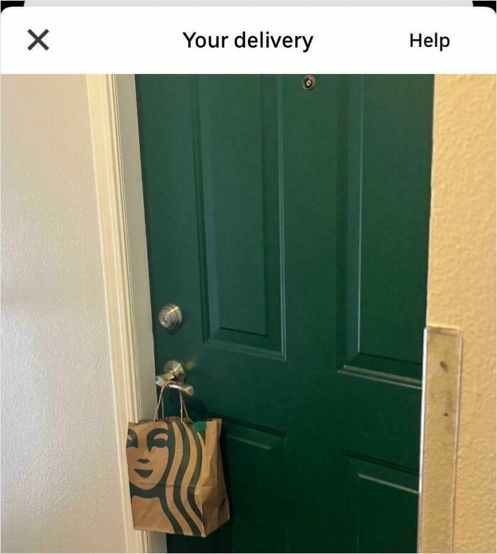 A green door with a Starbucks bag hanging on the doorknob, showing a funny food delivery placement.