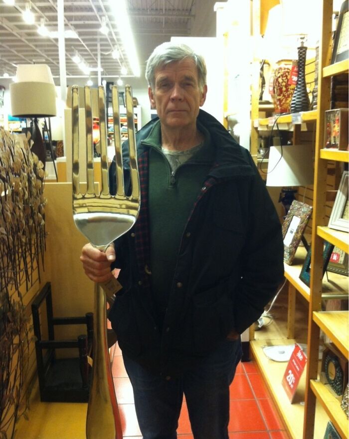 An amazing father holding a giant fork in a store aisle, looking seriously at the camera.