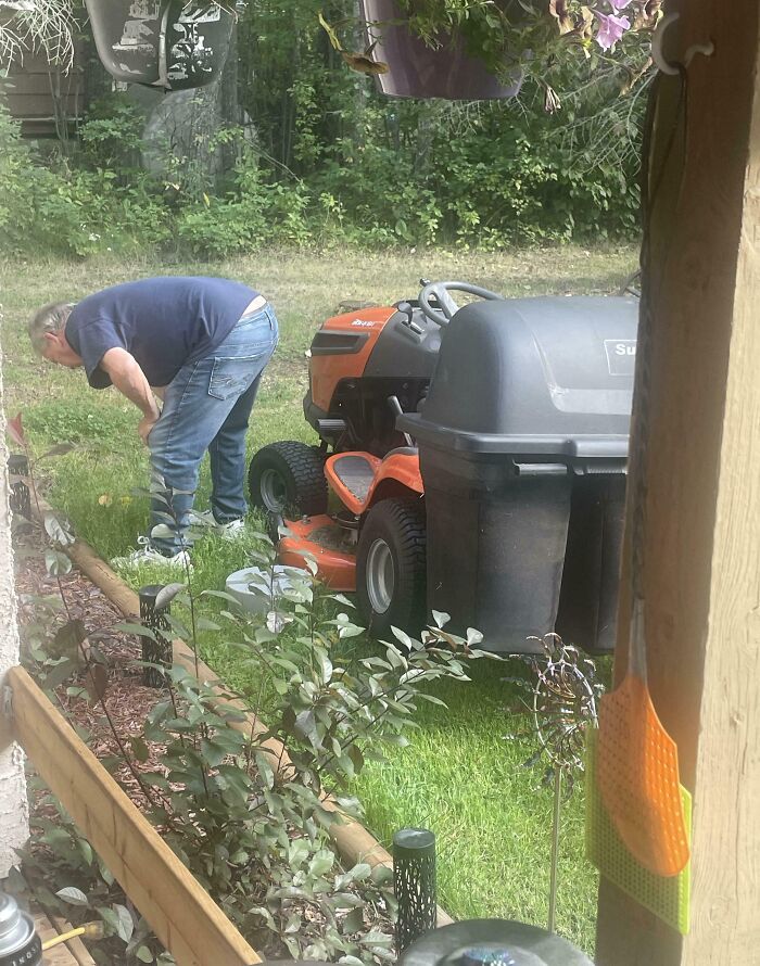 A dad tending to his lawn with a riding mower, an example of amazing fathers maintaining their homes.