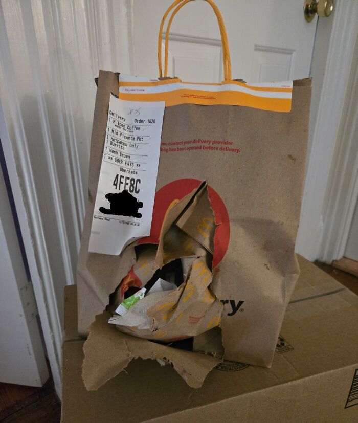 A torn food delivery bag from Uber Eats with contents spilling out, illustrating a food delivery fail.