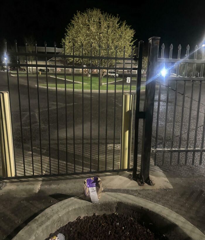 A brown paper bag, likely a food delivery, left outside a closed gate, an infuriating food delivery fail.