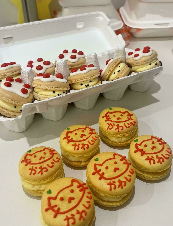 Adorable cartoon-face macarons in an egg carton and on a table, showcasing amazing baker treats.