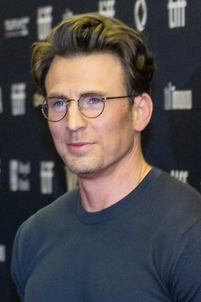 Close-up of Chris Evans wearing round glasses and a dark shirt at a film event